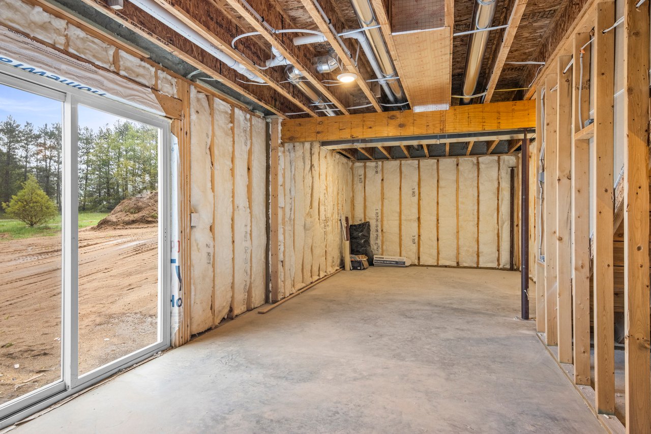 Unfinished home interior with insulated walls, exposed ceiling framing, and a sliding glass door.