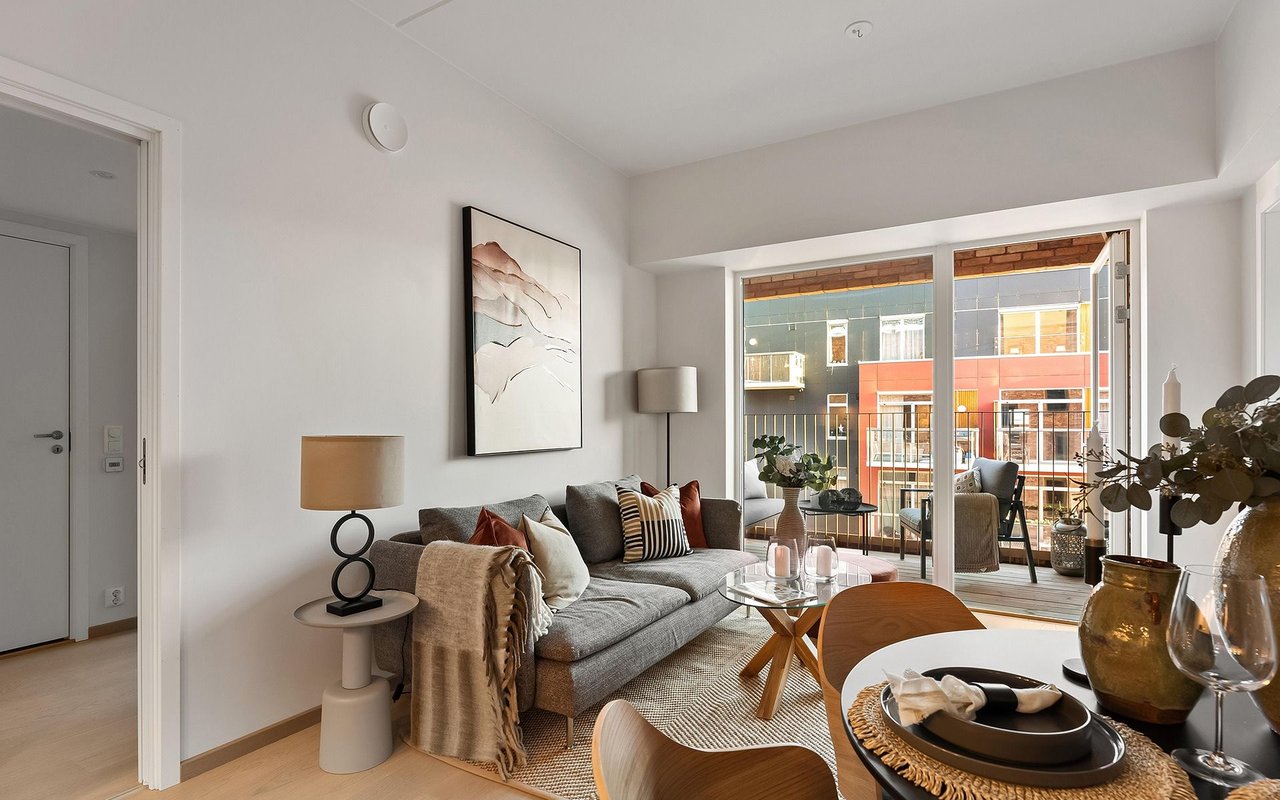 Furnished living room with a gray sofa and large windows opening onto a balcony.