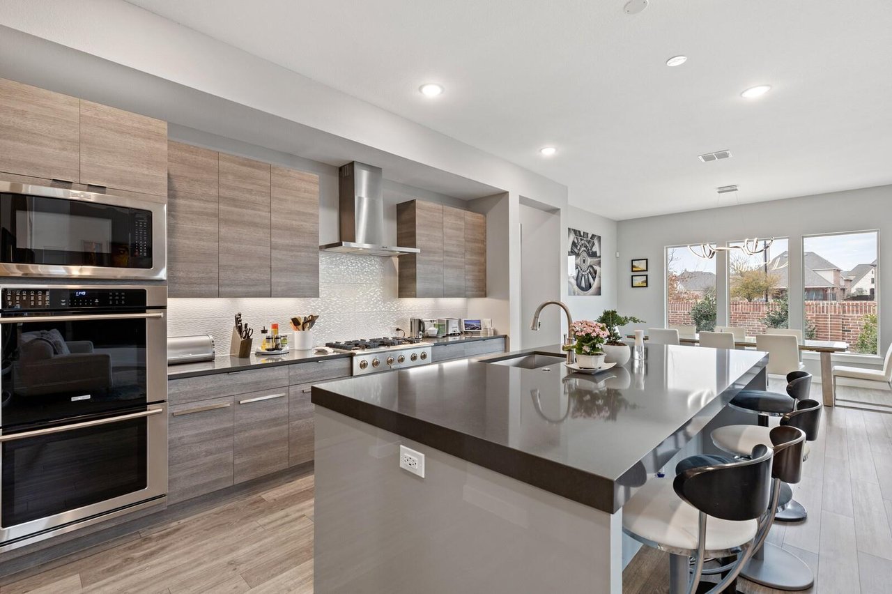 Designer kitchen with oversized island, quartz countertops, and stainless steel appliances in a luxury home in Phillips Creek Ranch, Frisco TX.