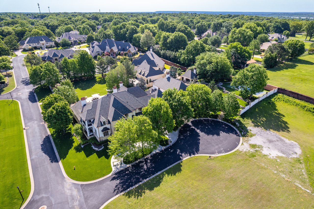 Aerial view of a leafy neighborhood with large homes along a curving street and cul-de-sac.