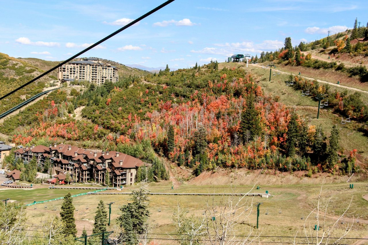 Autumn mountain resort with ski lifts, wooded slopes, and lodge buildings.