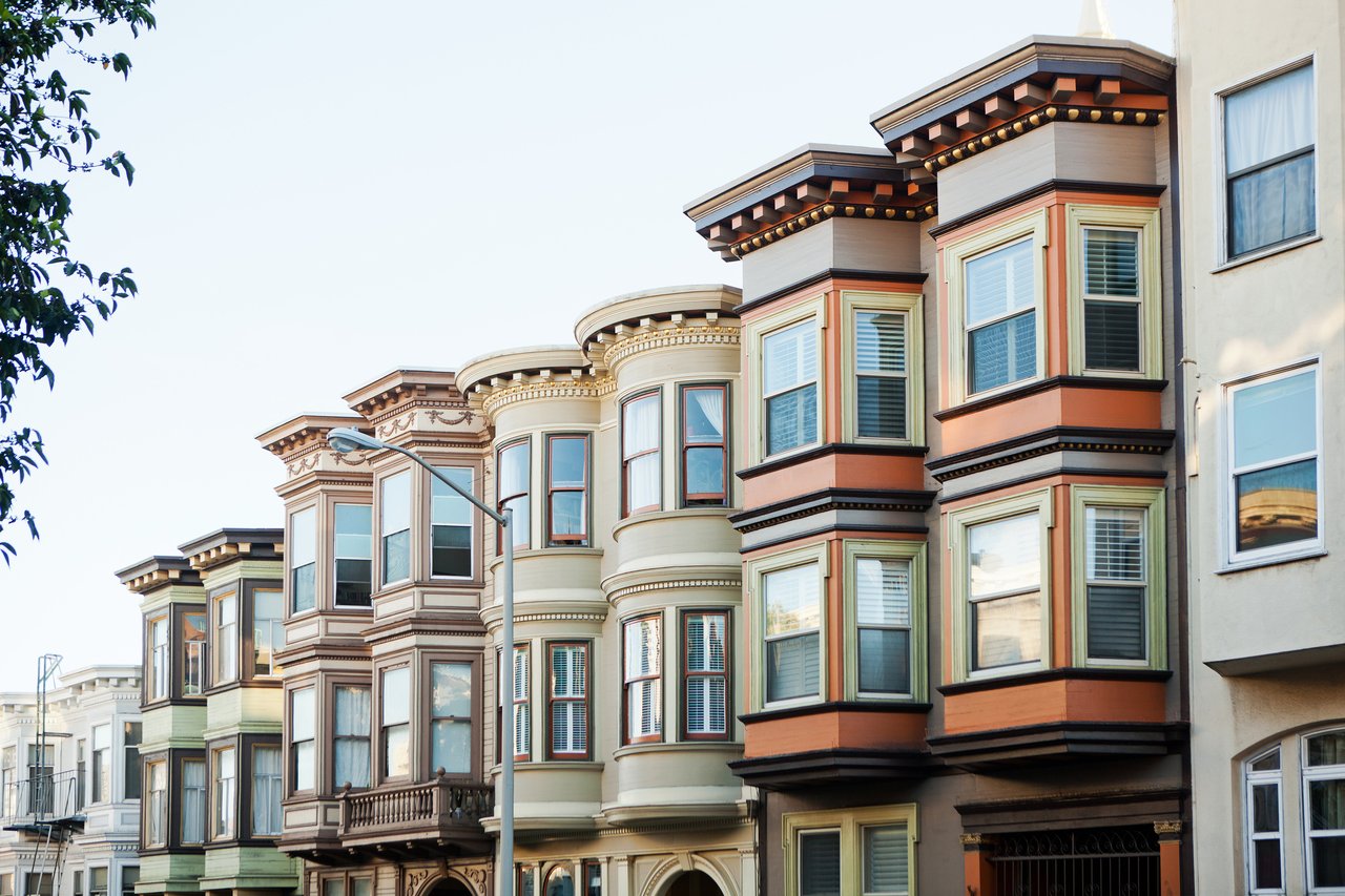 Row of colorful homes with bay windows and ornate trim.