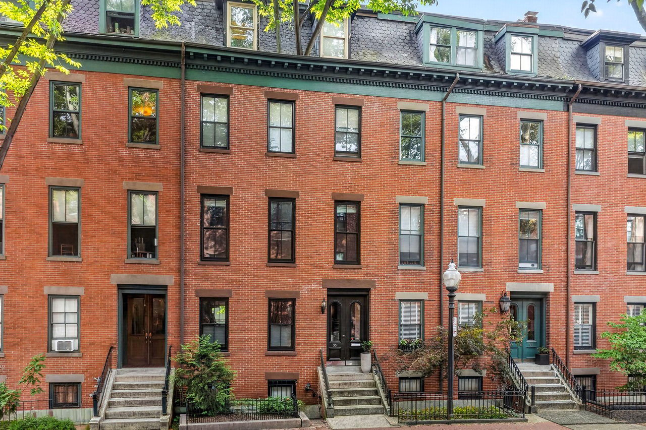 Red-brick South End townhouses with stone stoops, a slate mansard roof, and leafy front gardens.
