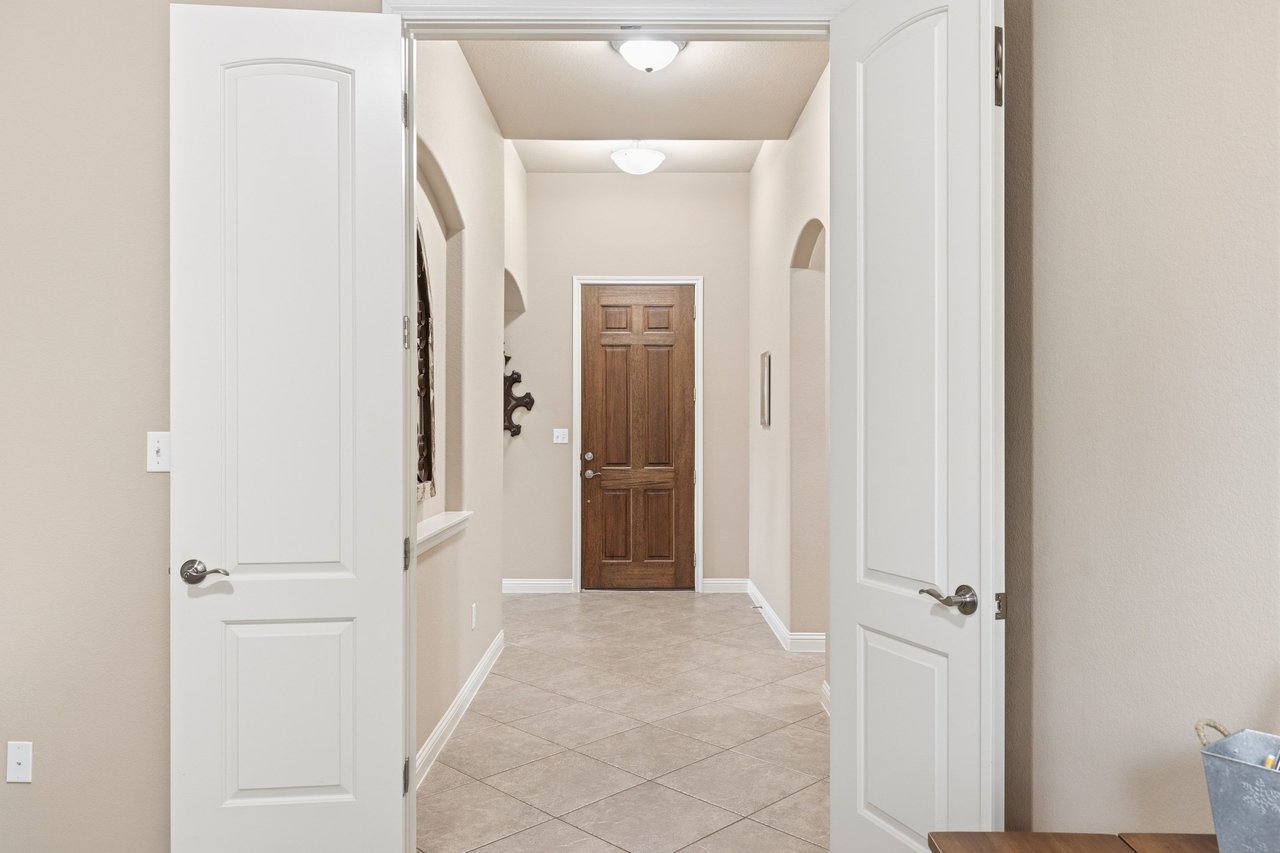 Entry hall with tiled floors, arched niches, and a dark wood front door.