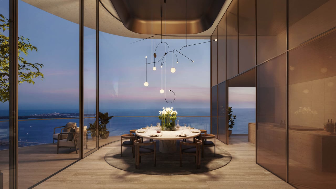 Dining room with a round table and floor-to-ceiling ocean views at dusk.
