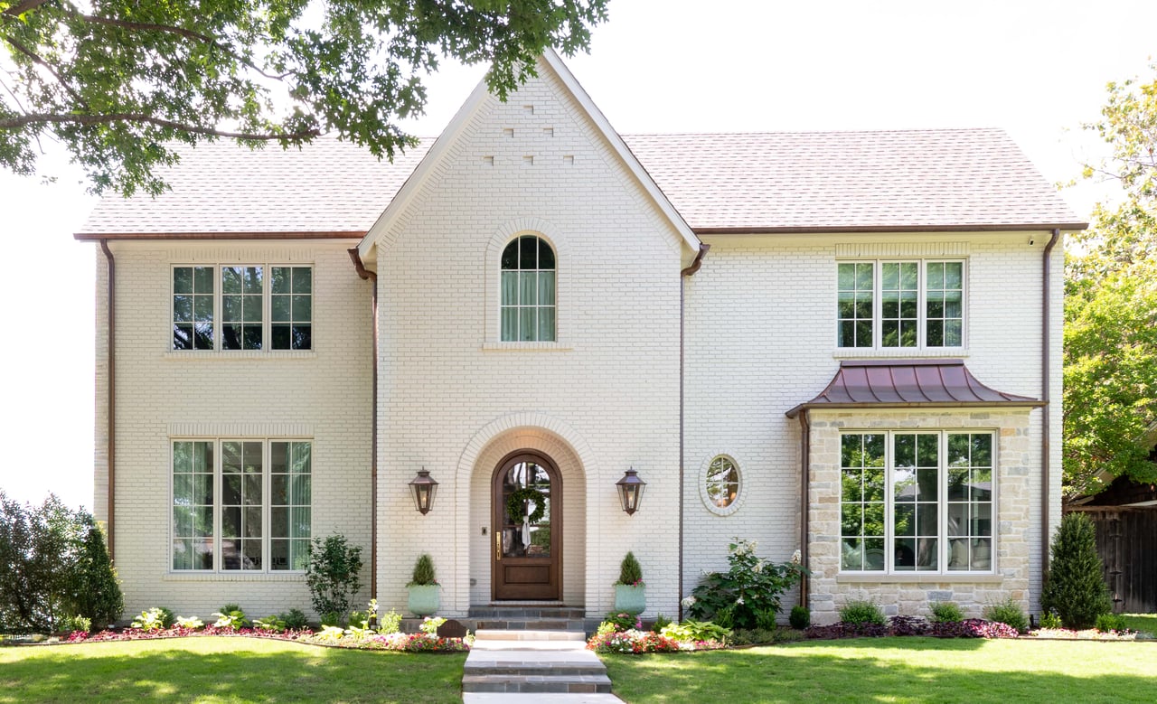 Two-story white brick home with a central arched entry and stone accents.