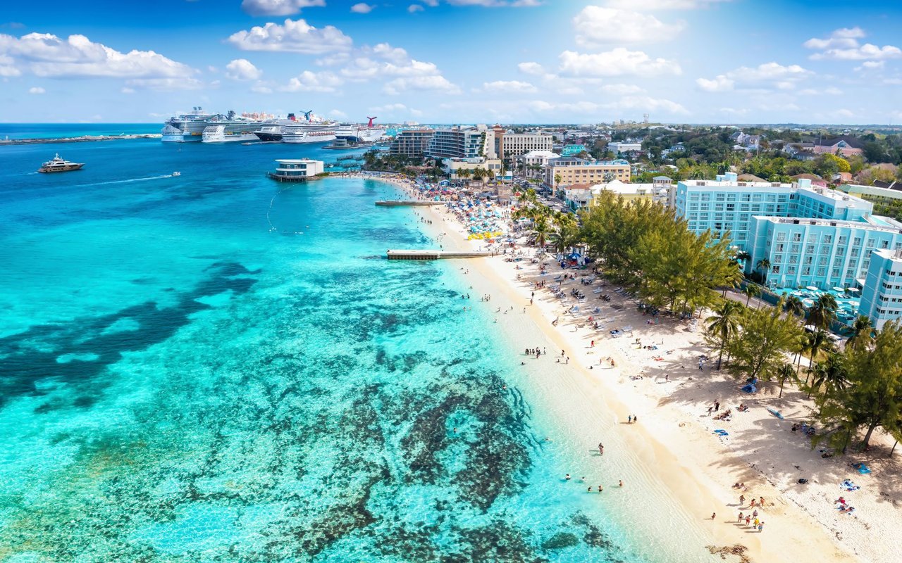 New Providence shoreline with turquoise water, a crowded sandy beach, hotels, and cruise ships.