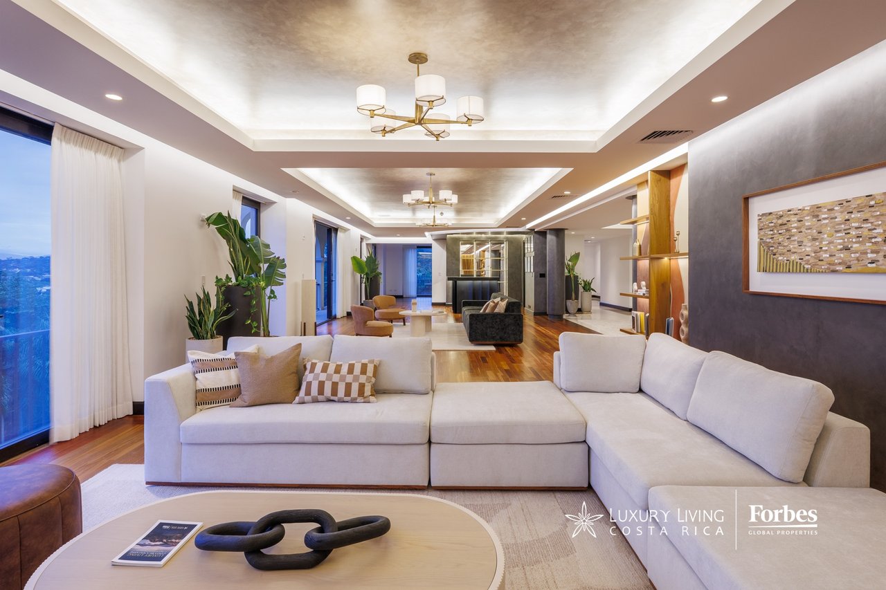 Penthouse living room with a white sectional, hardwood floors, and large windows.