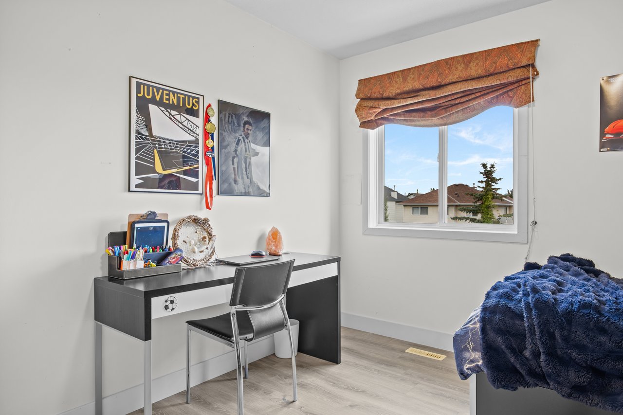 Bedroom with a desk, Juventus poster, patterned window shade, and a bed covered in navy blue bedding.