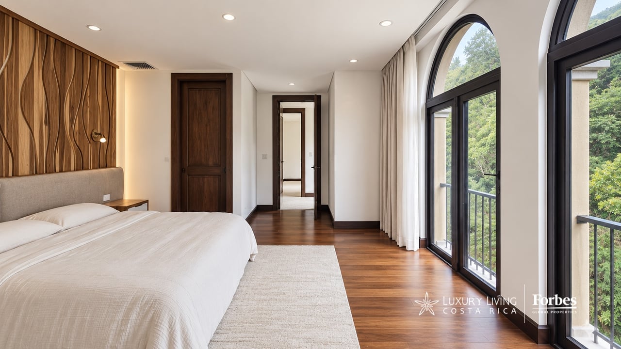 Penthouse bedroom with a sculptural wood accent wall and tall arched windows overlooking greenery.
