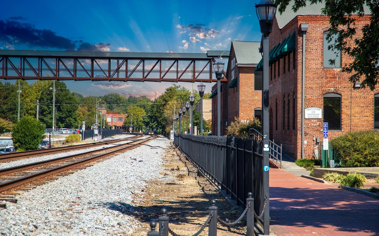 Railroad tracks curve past Marietta Station’s brick building beneath a pedestrian bridge.