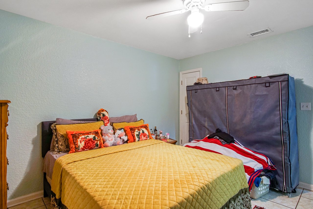 “Bedroom at 2506 Nugget Lane in Tallahassee, Florida, with tile flooring, light green walls, and a ceiling fan with light fixture. The room is shown with a bed centered against the wall and a door to the closet in the corner, offering functional space for storage.