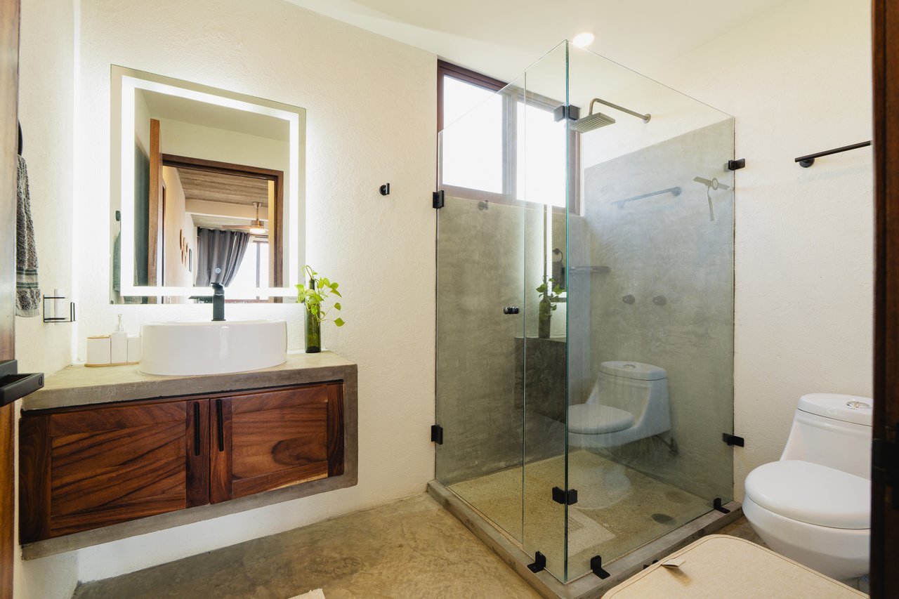 Bathroom with a floating wood vanity, vessel sink, and glass-enclosed shower.
