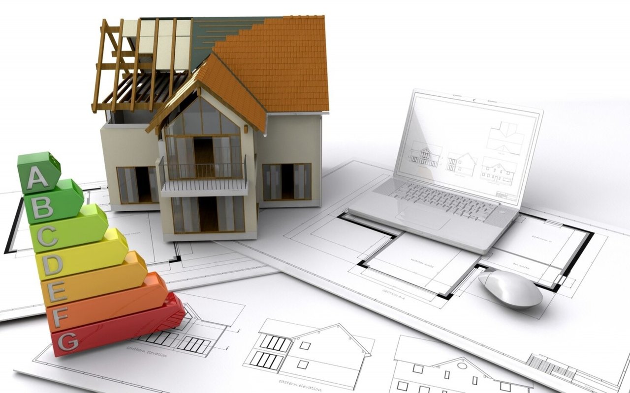House model, A–G energy-efficiency scale, and laptop on architectural plans.