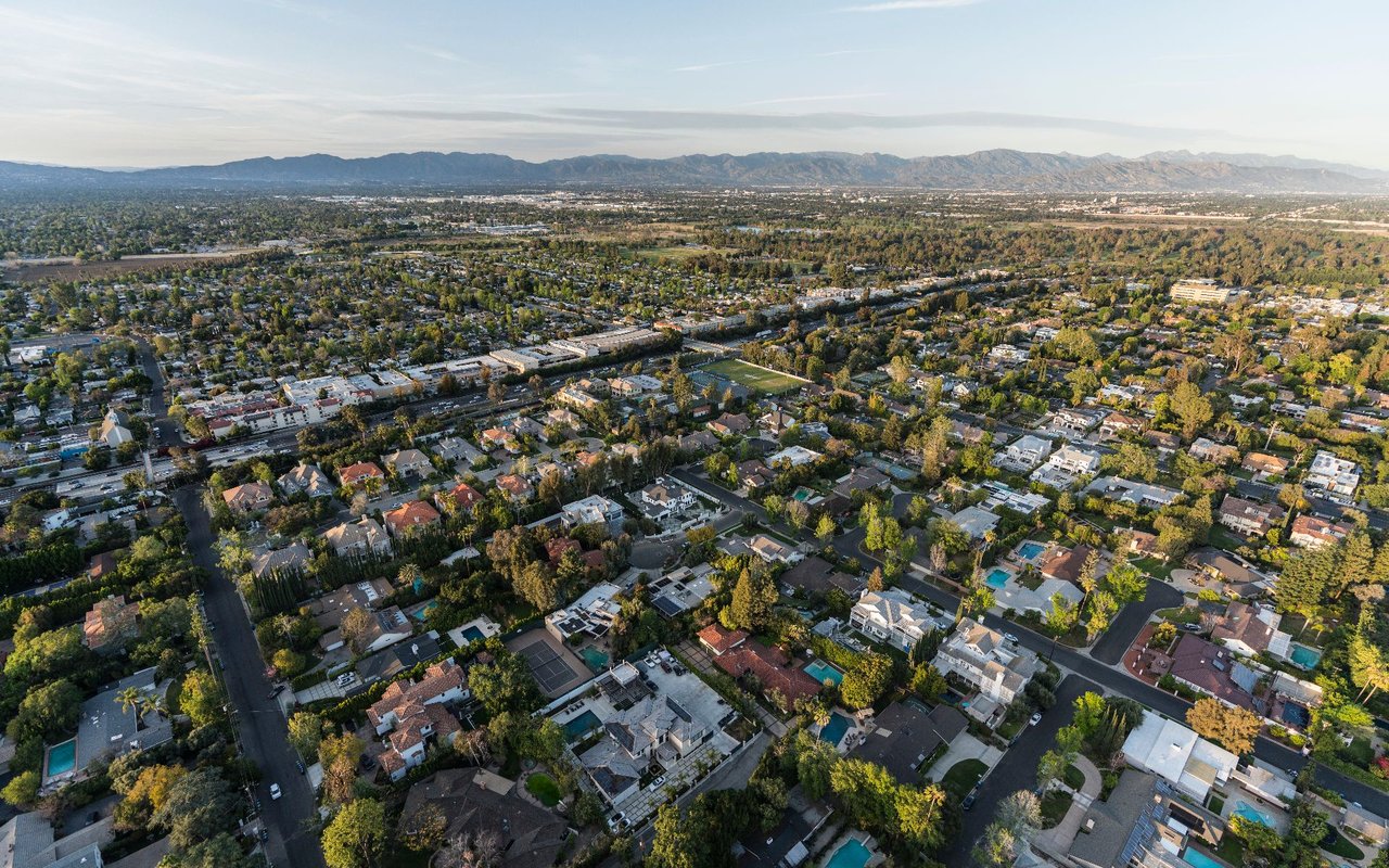 Aerial view of Encino’s tree-lined neighborhoods with mountains on the horizon.