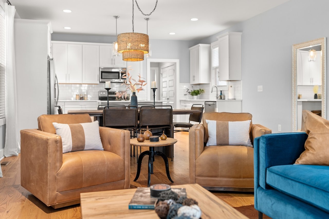 Living room at 6117 California Ave #B — tan sofa, chandelier, open to kitchen