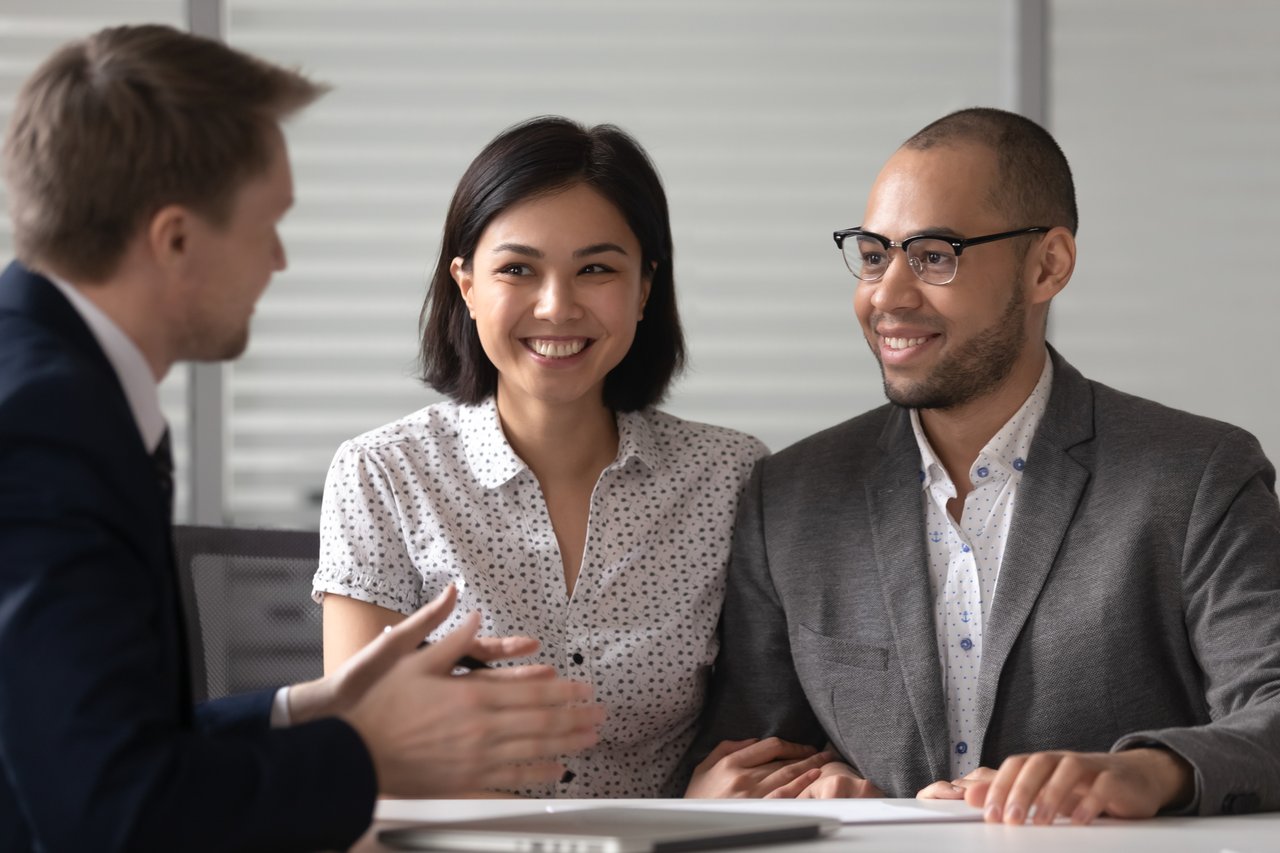 Couple meeting with real estate agent in an office to discuss buying or selling a home.