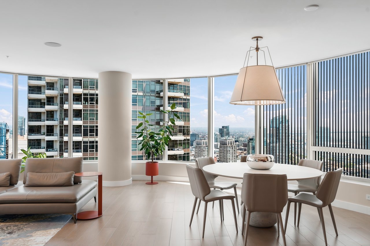 High-rise living and dining area with floor-to-ceiling windows overlooking the downtown skyline.