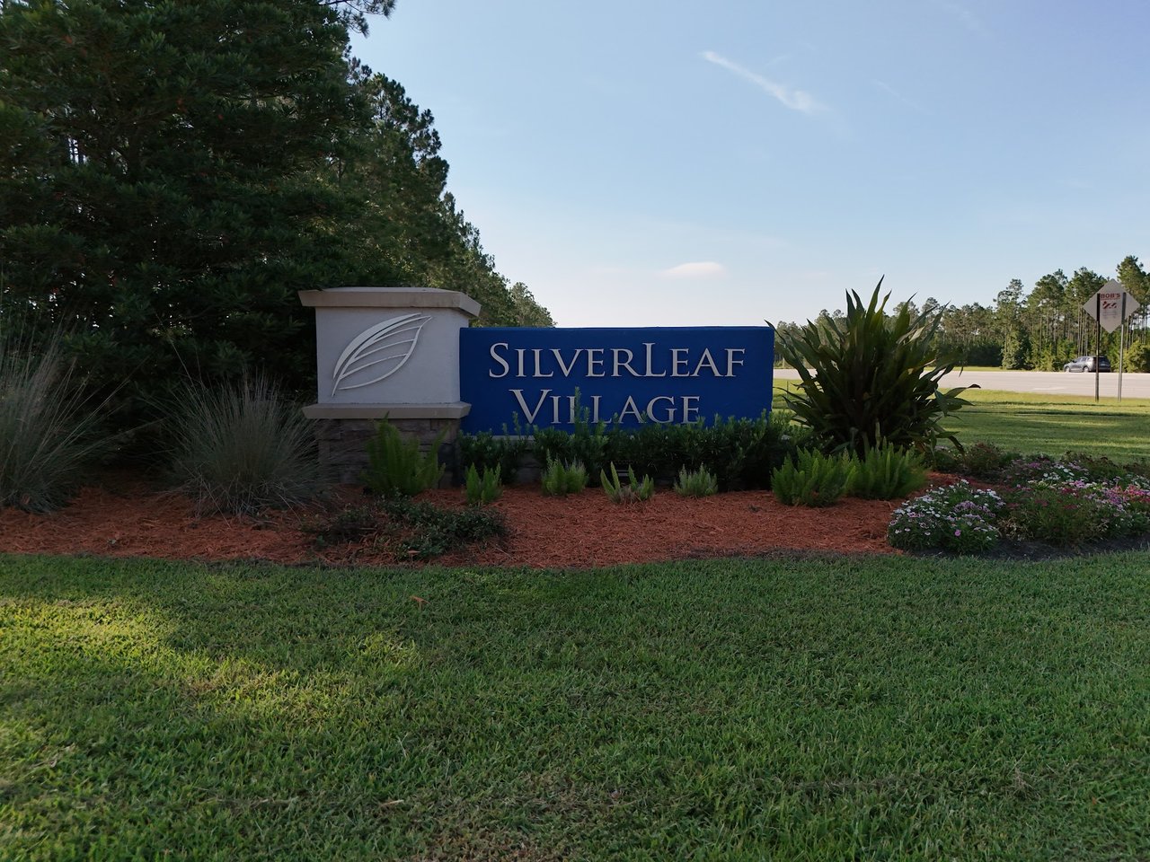 Silverleaf Village entrance sign amid landscaping and pine trees.