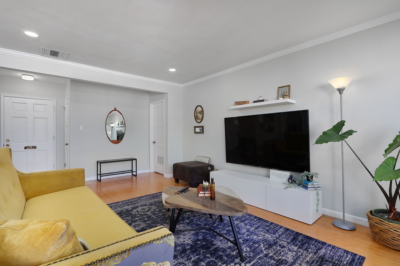 Spacious Lake Balboa living room with crown molding, light staging, and view of entry hallway