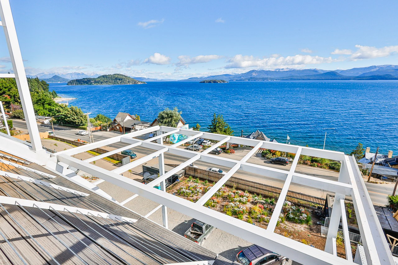 Lake and mountain view beyond a white pergola, with wooded islands in the distance.