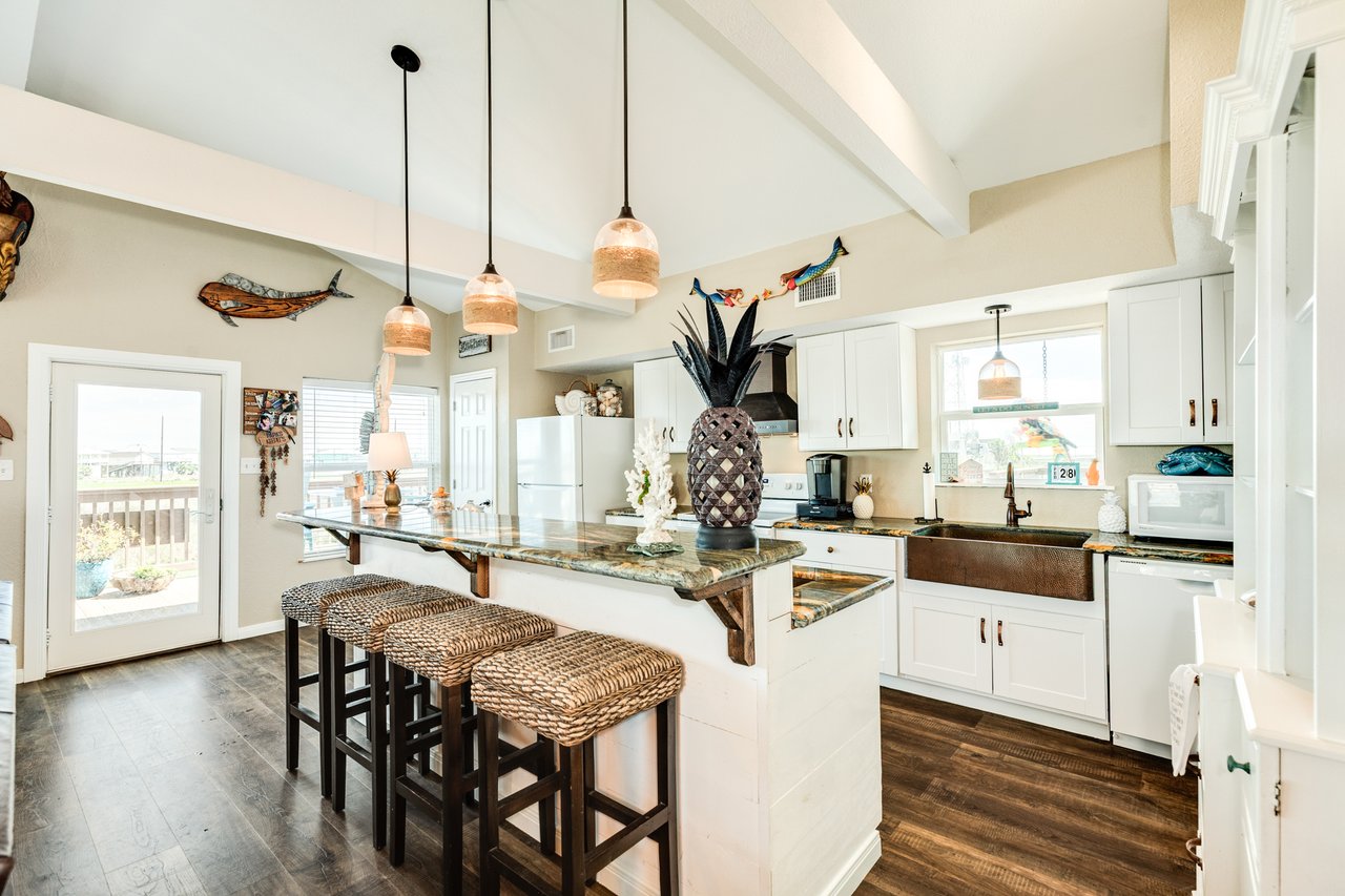 Close-up video of custom granite countertops in a coastal home at 123 Pieces of Eight, Freeport TX, showcasing high-end finishes in the open-concept kitchen with water views.