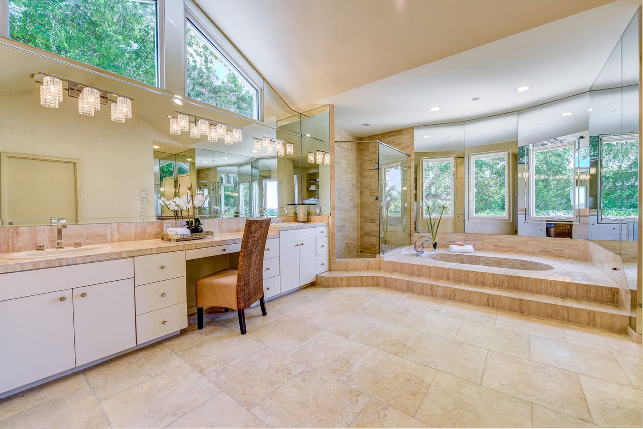 Primary bathroom at 3304 Barton Creek Blvd, Austin, with travertine tile, a step up soaking tub, and a glass walk in shower.