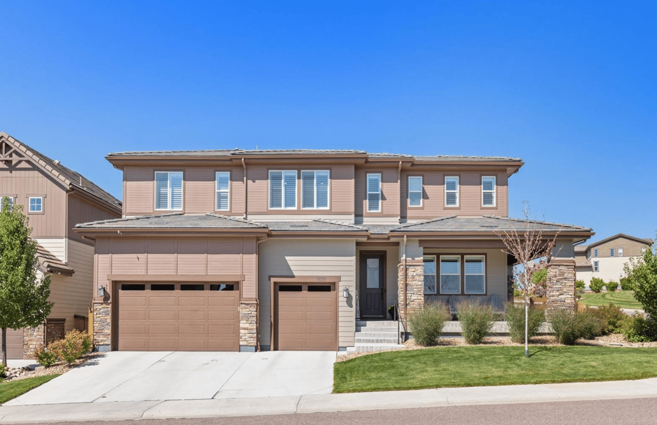 Two-story taupe home with stone accents, double garage, and landscaped front yard.