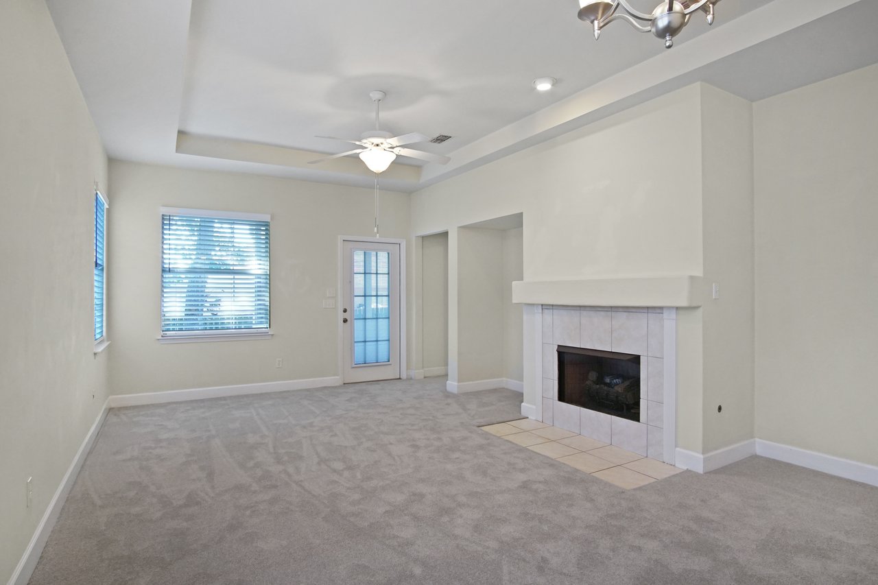 Living room at 5441 Hampton Hill Circle, Tallahassee, Florida 32311 with fireplace, tray ceiling, ceiling fan, and door to screened porch.