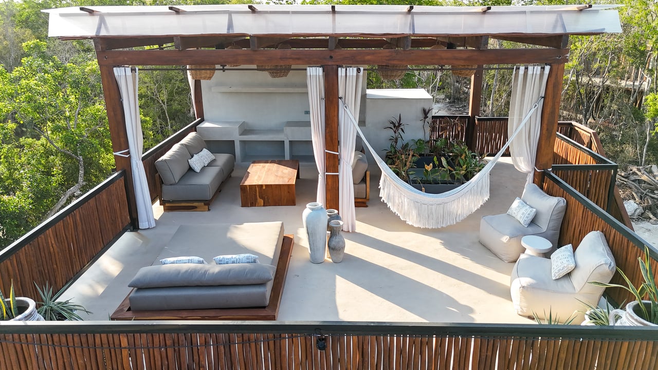 Furnished rooftop terrace with lounge seating, a hammock, and views of surrounding greenery.