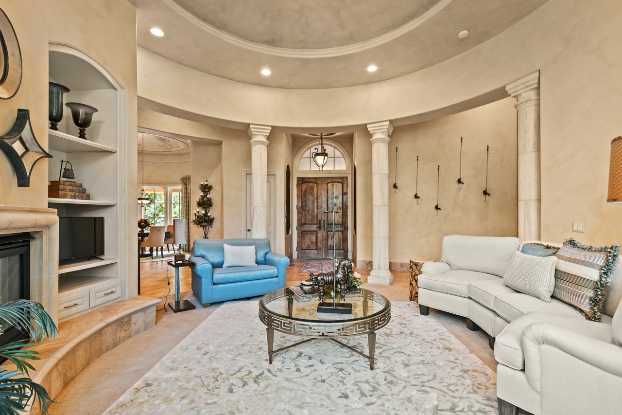 Living room with curved ceiling, classical columns, blue loveseat, and white sectional.