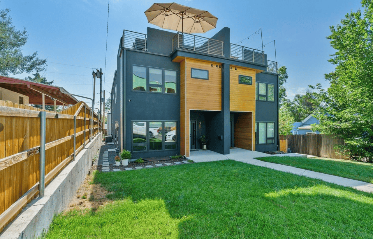 Modern two-story home with wood accents, rooftop terrace, and grassy backyard.