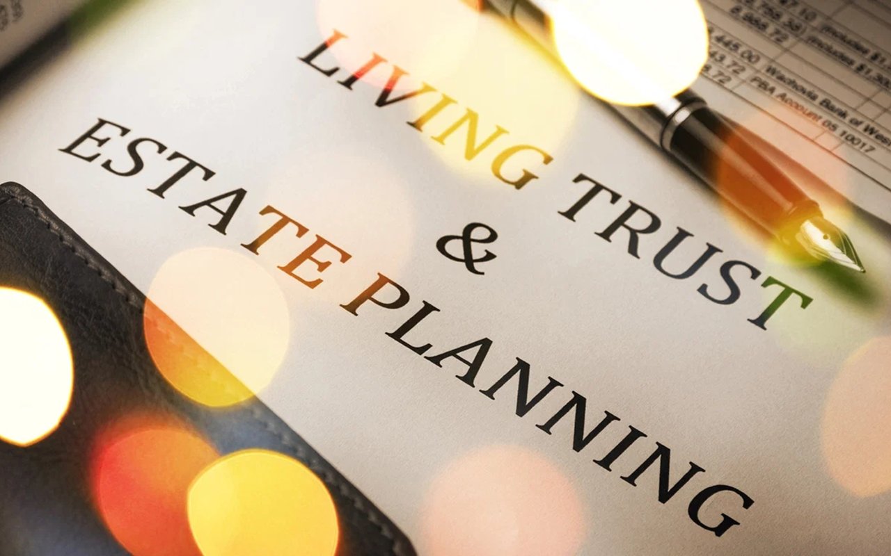 Living trust and estate planning document beside a pen and magnifying glass.