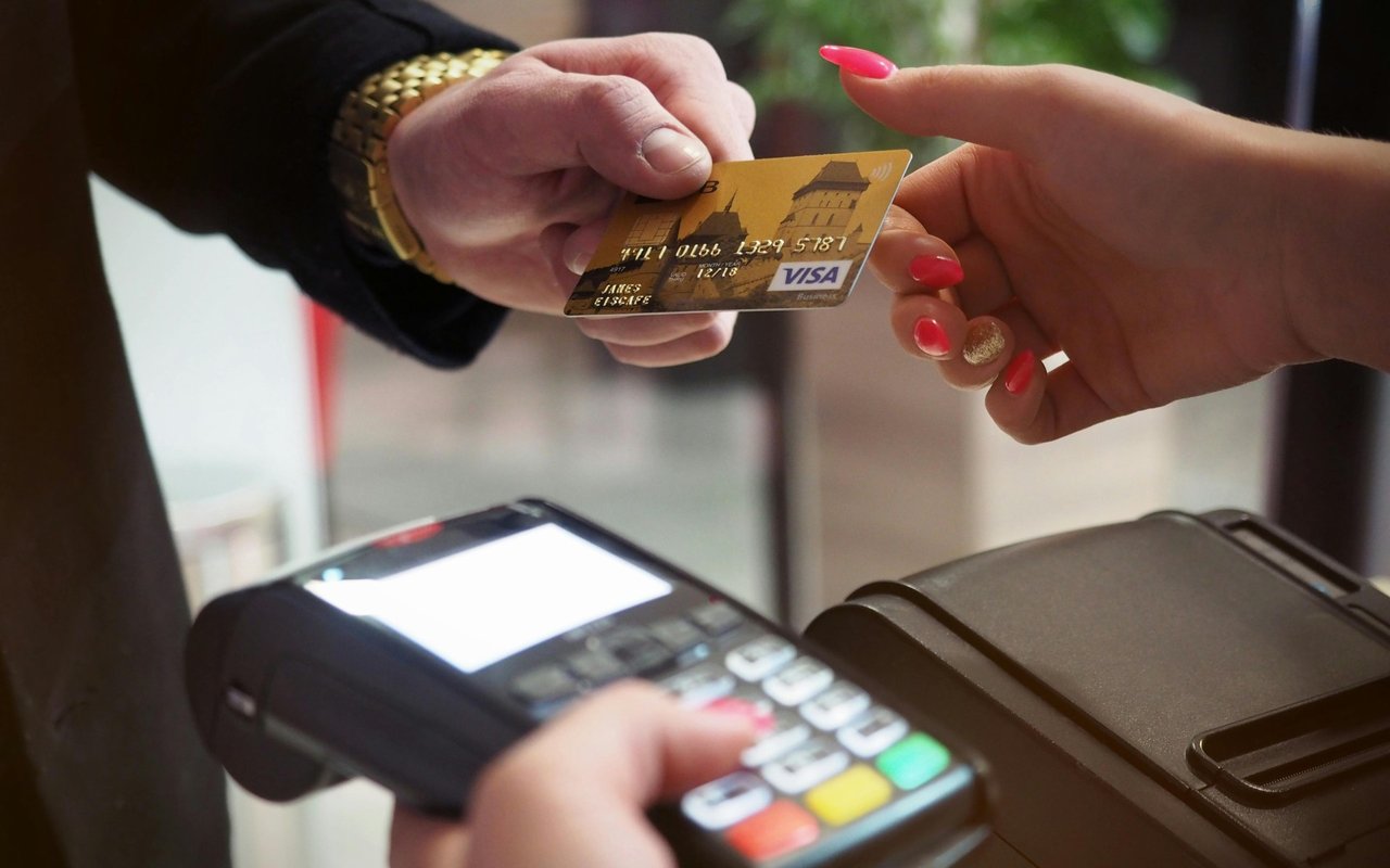 Hands exchange a VISA card over a payment terminal.