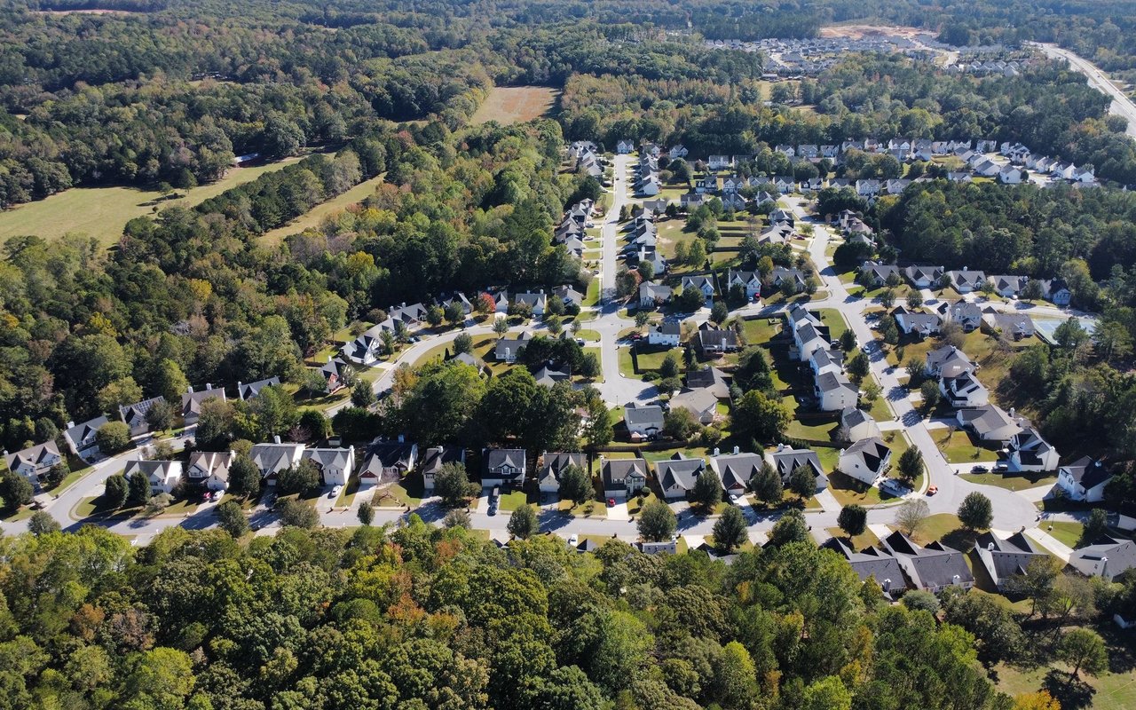 Aerial view of a leafy neighborhood with detached homes and curving streets.