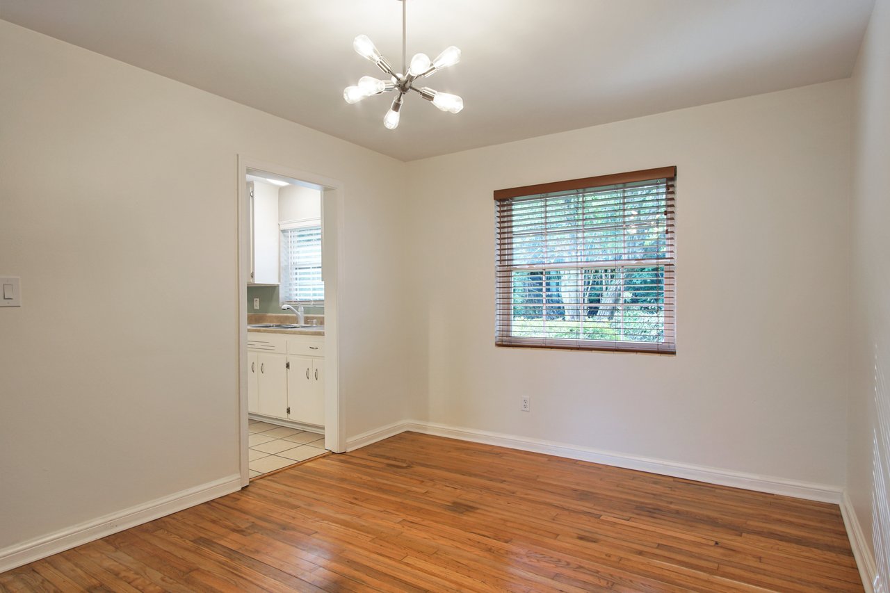 A well-lit room featuring hardwood floors and a large window, creating a warm and inviting atmosphere.