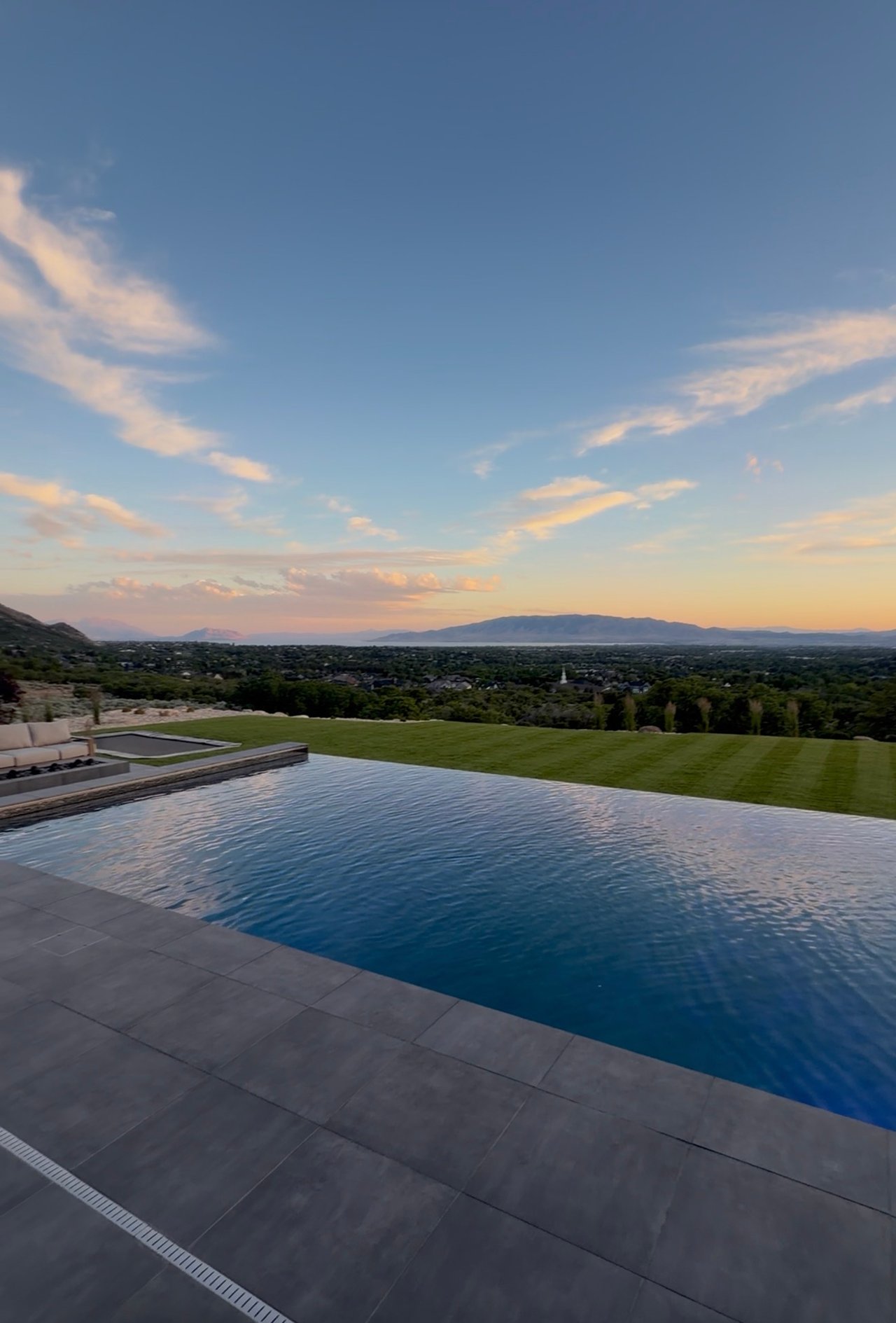 An infinity pool overlooking Utah Valley at sunset with mountains and a golden sky in the background