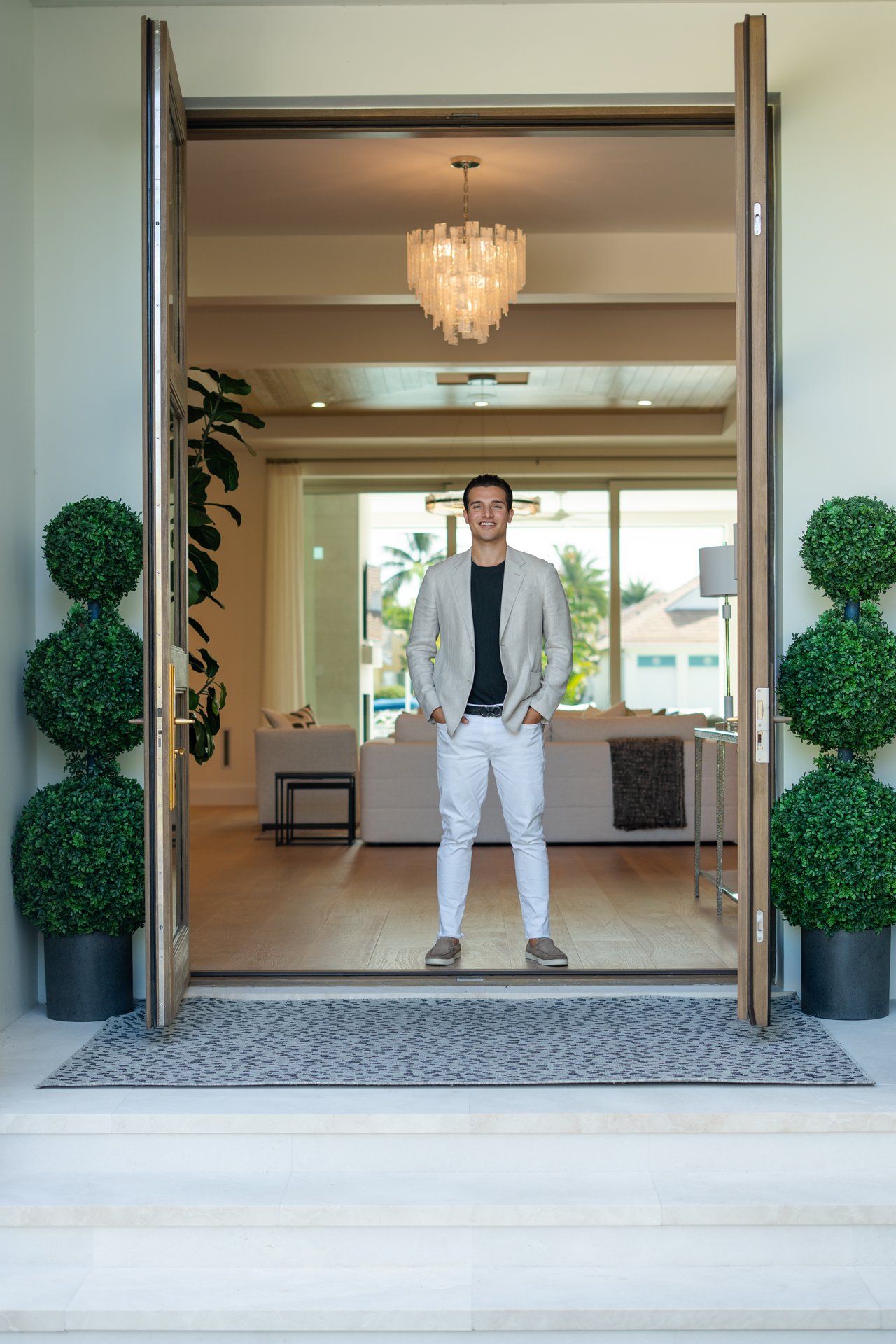 Mario Furillo standing in an open doorway, with a chandelier and living room behind him.