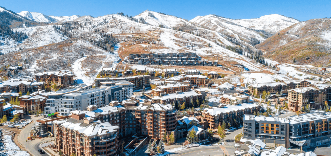 Aerial view of Canyons Village buildings beneath snow-covered mountain slopes.