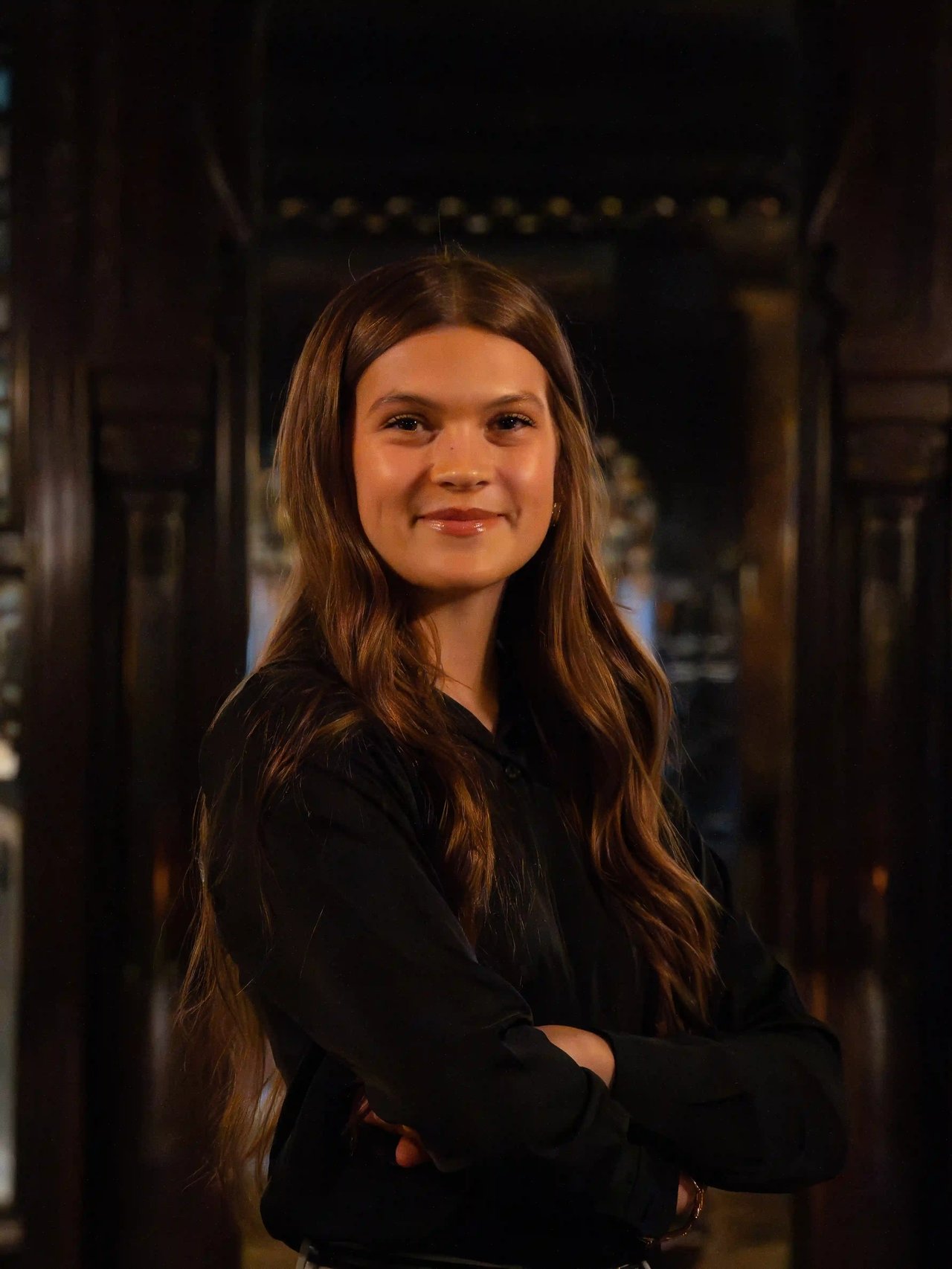 Quincy Markee, Milwaukee realtor with the Luxe Haven Group, smiling with arms crossed inside an elegant interior.