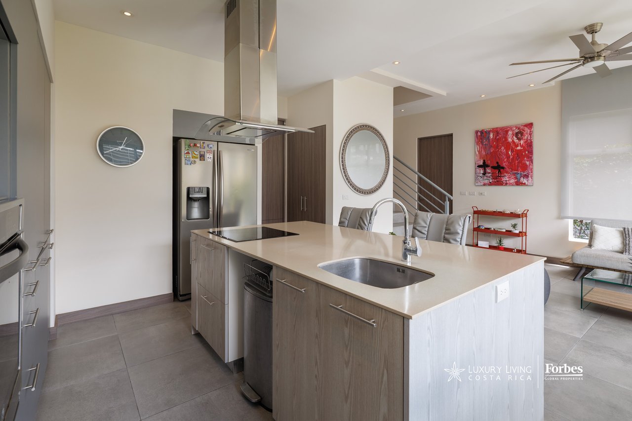 Open-plan kitchen with a large island, stainless steel appliances, and an adjoining living area.