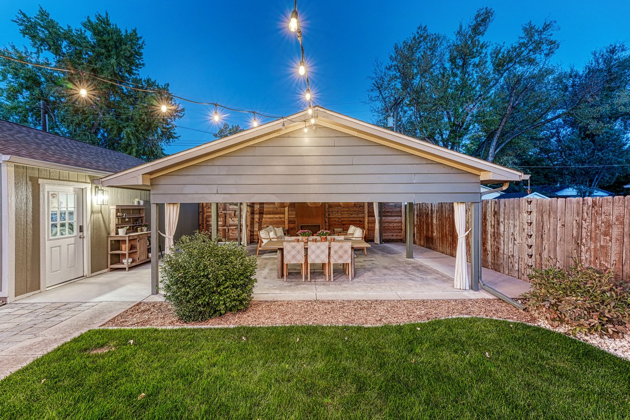 Covered patio at dusk with string lights, seen from the lawn