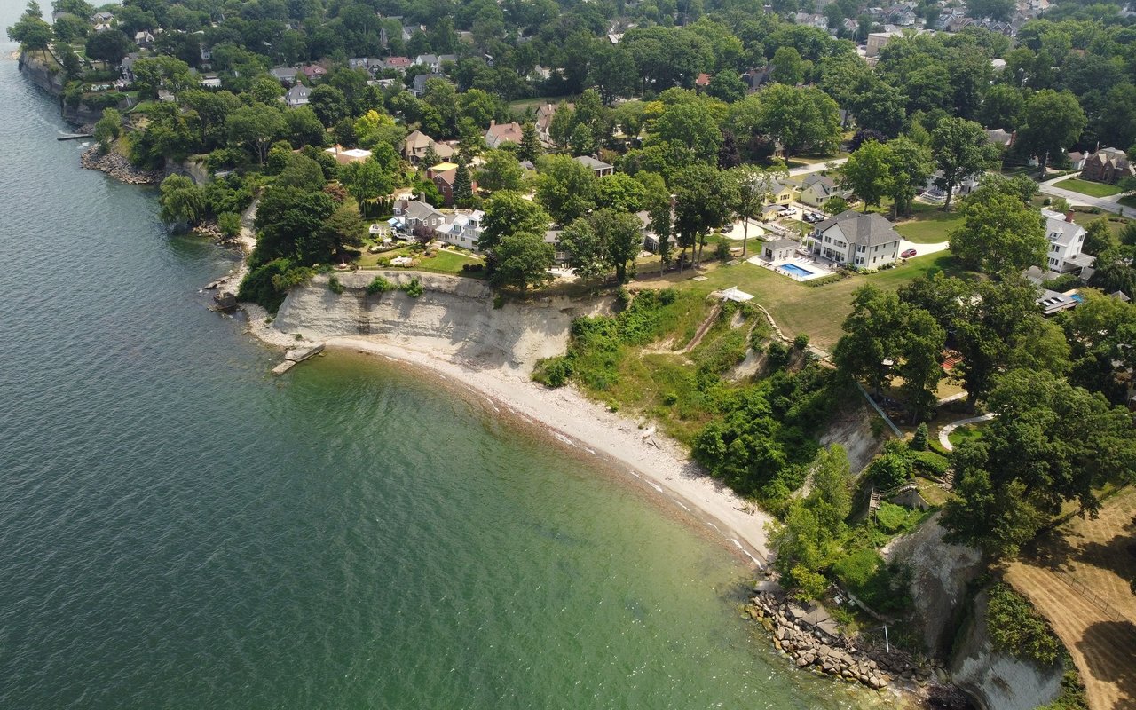 Aerial view of lakeside homes above pale bluffs and a narrow beach.