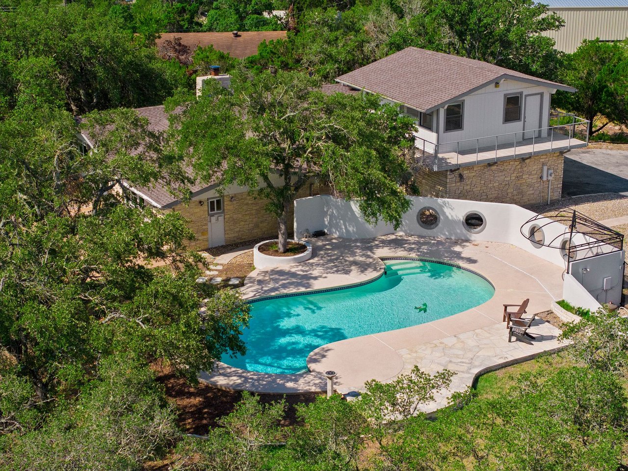 Aerial view of the pool and mature oak-shaded grounds at 3935 Lago Vista Drive, a hilltop Mid-Century Modern home overlooking Lake Travis in the Highland Club Village area of Austin, TX.