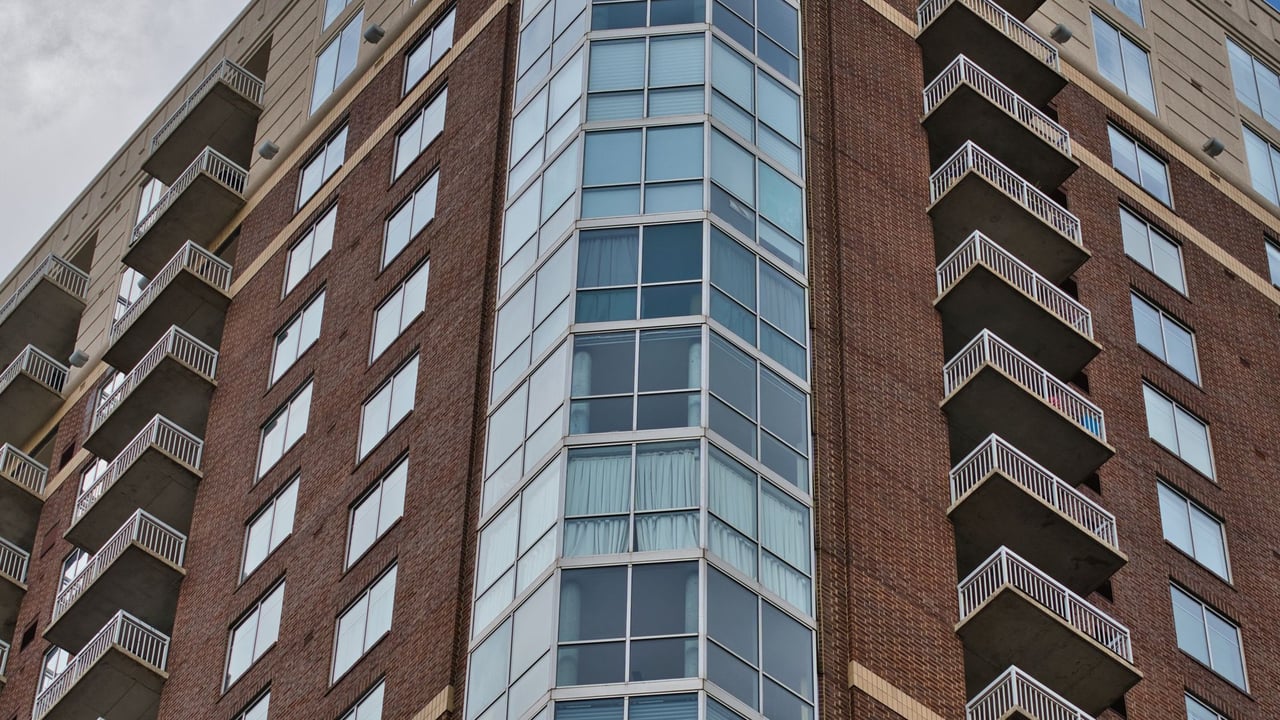 Low-angle view of a brick and glass high-rise condo tower in Atlanta against a blue sky