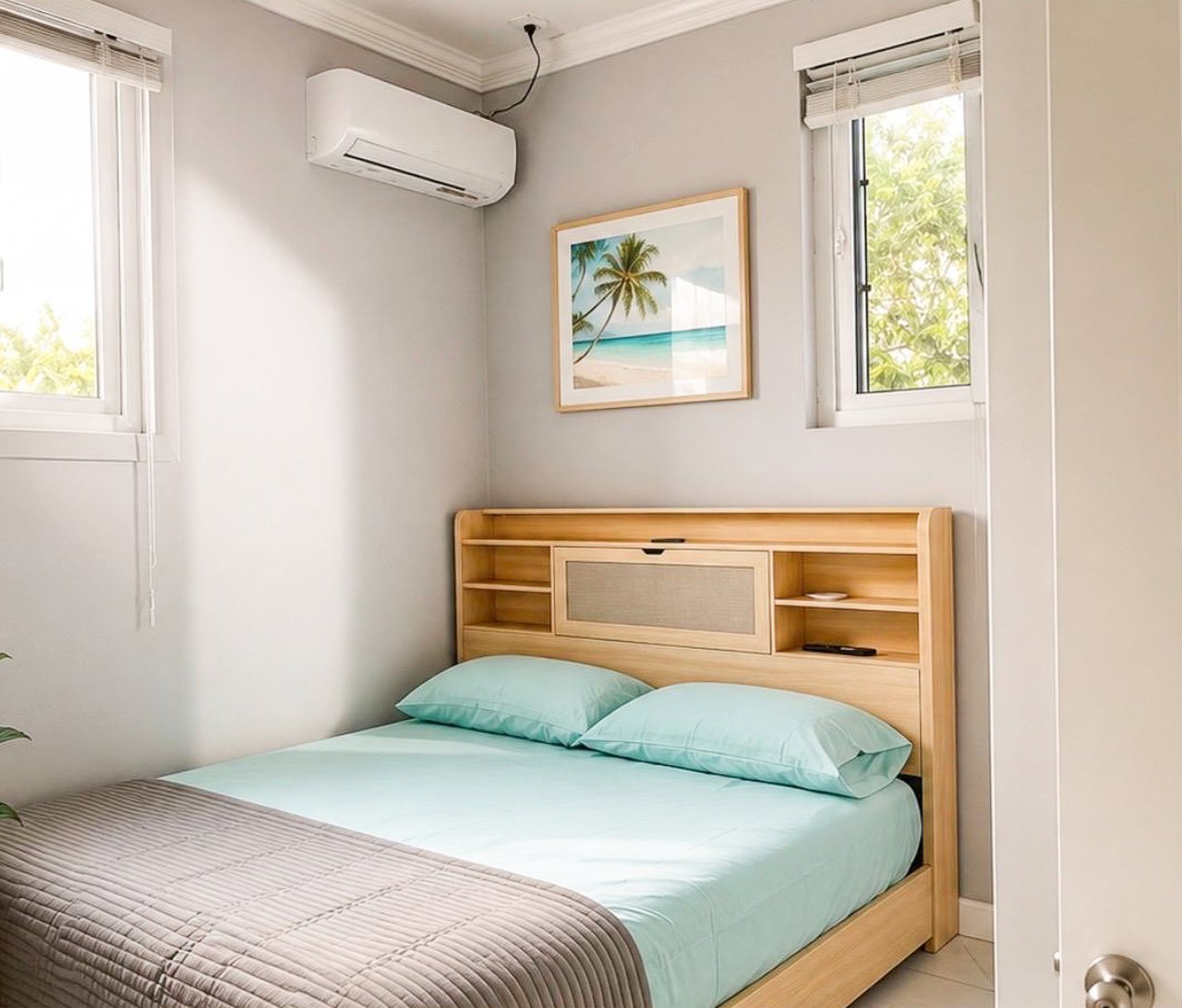 Bedroom with pale aqua bedding, a light wood bed, two windows, and a wall-mounted air conditioner.