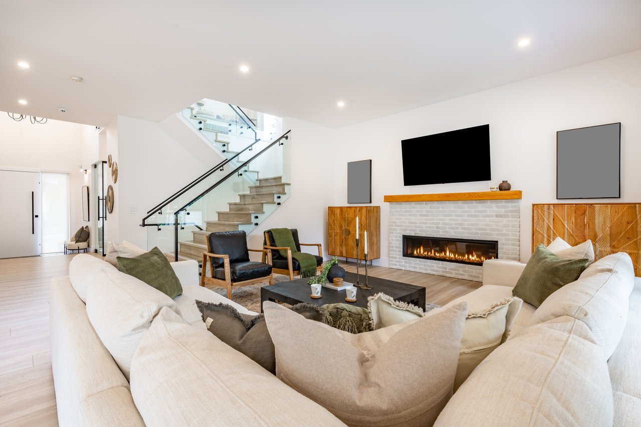 Modern living room with a glass-railed staircase and linear fireplace.