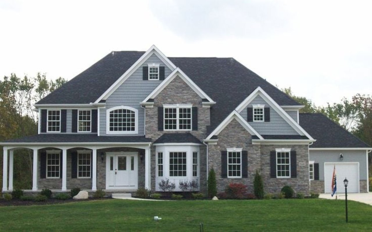 Gray two-story house with stone accents, a covered porch, and an attached garage.