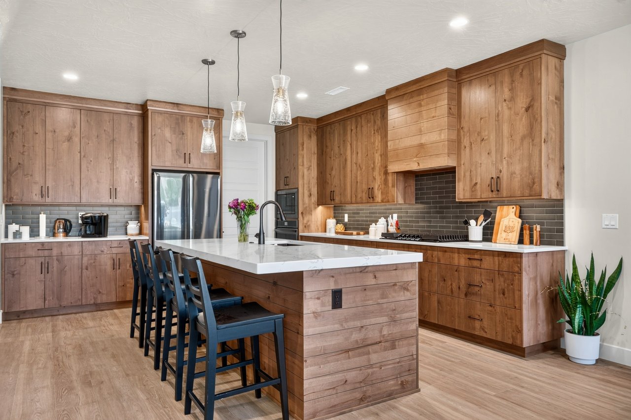 Kitchen with wood cabinets, a large white island, and dark tile backsplash.