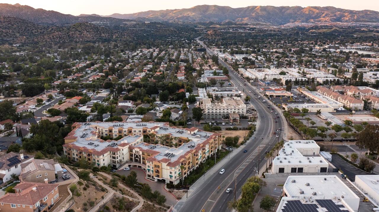 Aerial view of Chatsworth with a major road, neighborhood buildings, and mountains in the background.